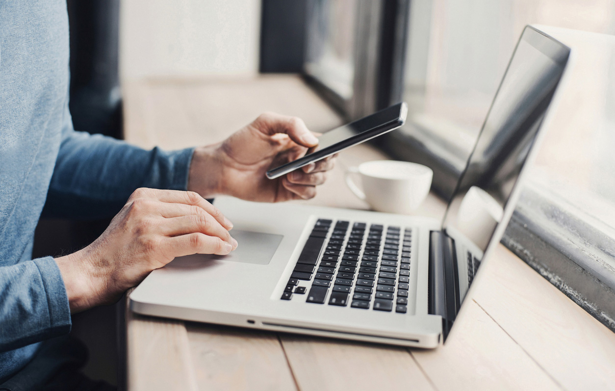 Men student is typing on laptop computer and using smartphone