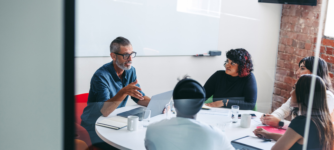 Experienced mature businessman briefing his colleagues in a meeting. Businesspeople having a discussion in a modern workplace. Group of creative businesspeople working as a team.