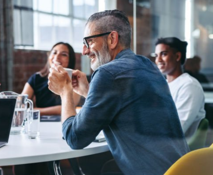 A professional drinks coffee during a team meeting at his firm